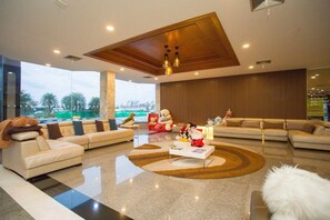 A modern living room with a large window, a sofa set, a coffee table, and a decorative rug. - CBD 2 Hotel (Surat Thani)