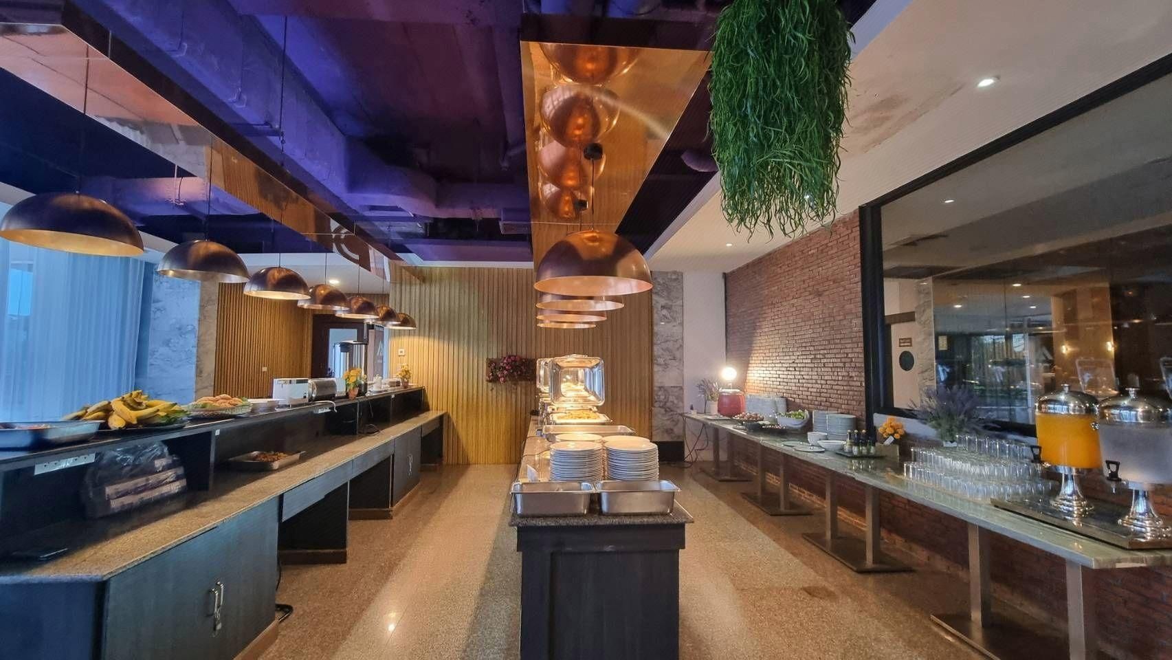 A modern kitchen with a central island, pendant lighting, and a brick wall.