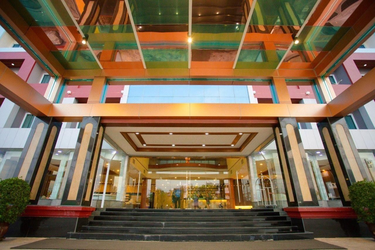 A multi-level hotel entrance with glass railings, a staircase leading to the lobby, and a modern architectural design.
