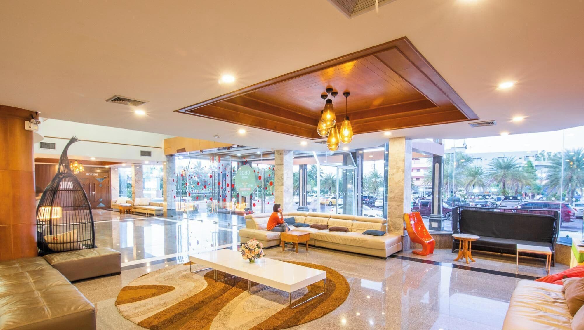 A spacious lobby with a central seating area, a coffee table, and a large window offering a view of the street.