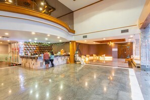 Eine Hotelhalle mit Empfangsschalter, Sitzgelegenheiten und einer Treppe.