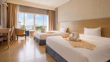 A hotel room with two beds, a desk, and a view of the city.