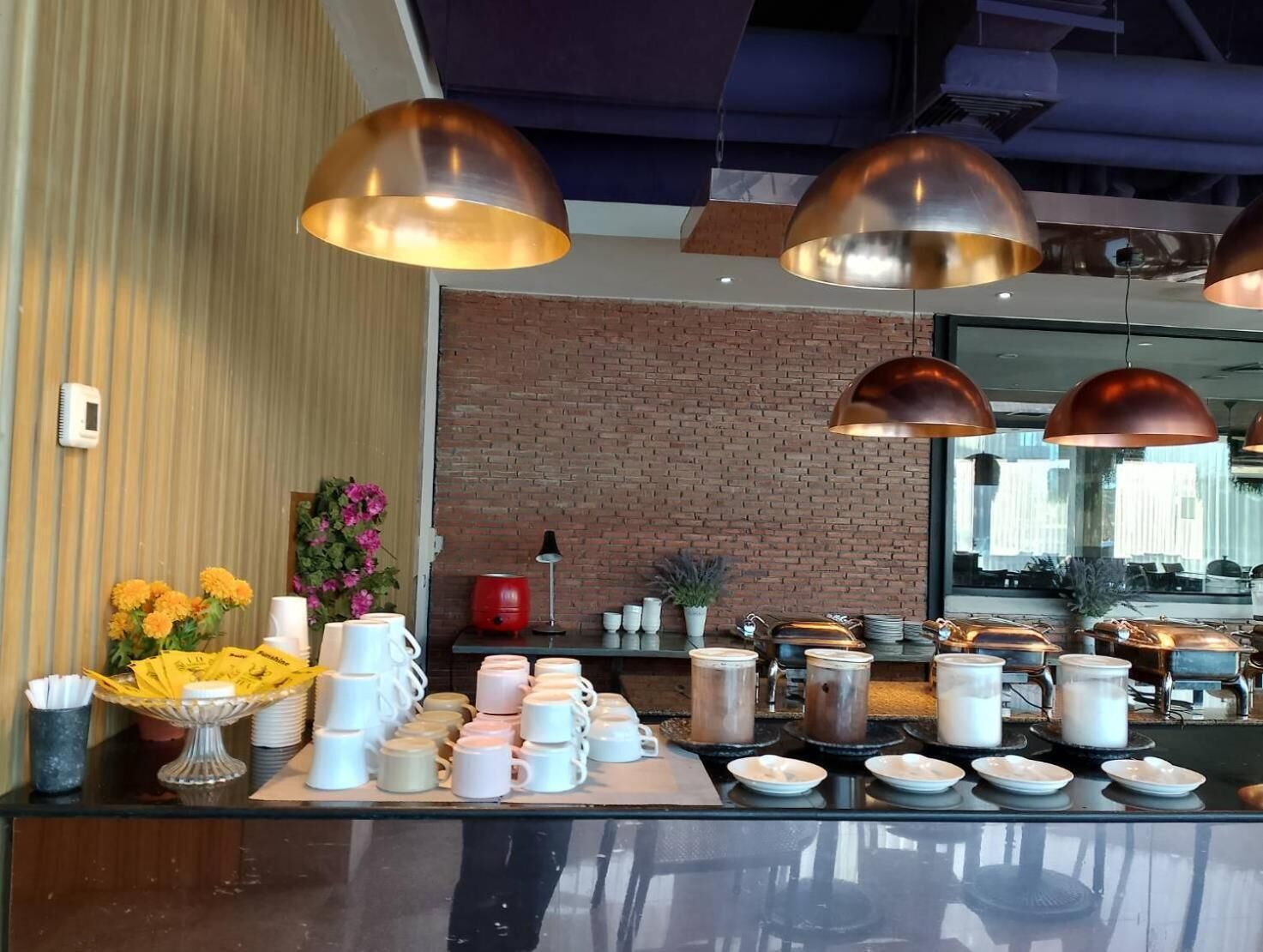 A buffet setup with multiple serving stations, a brick wall, and pendant lighting.