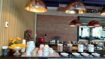 A buffet setup with multiple serving stations, a brick wall, and pendant lighting.