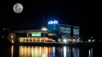 A hotel with a 'cbd2' sign, a reflection in the water, and a full moon in the sky.