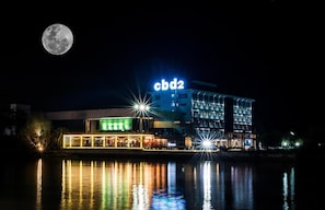 Un hotel con un letrero 'cbd2', un reflejo en el agua y una luna llena en el cielo.