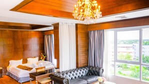A hotel room with a bed, a leather sofa, a dining table, and a chandelier. - CBD 2 Hotel (Surat Thani)