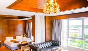 A hotel room with a bed, a leather sofa, a dining table, and a chandelier. - CBD 2 Hotel (Surat Thani)
