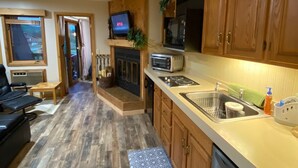 A compact kitchen with wooden cabinets, a microwave, a toaster, and a fireplace.