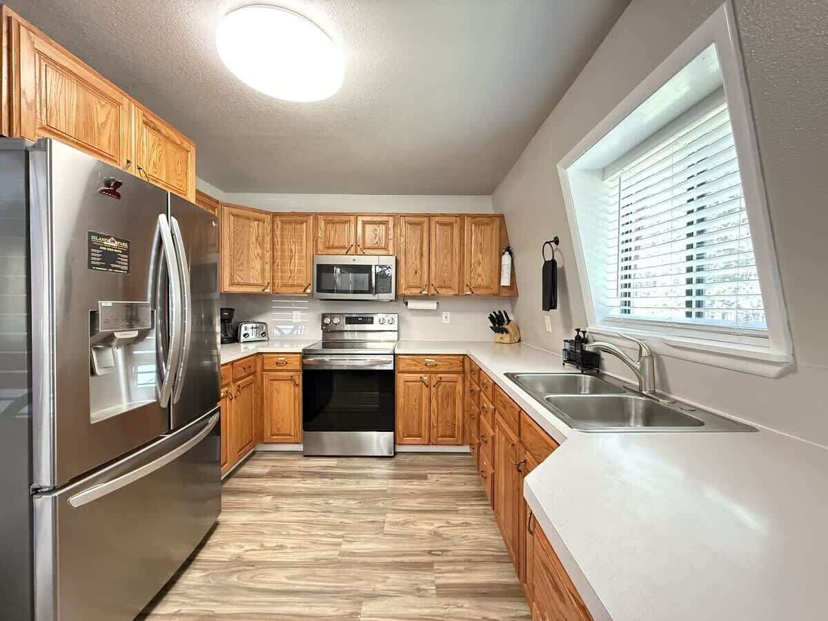 A modern kitchen with wooden cabinets, stainless steel appliances, and a window providing natural light.