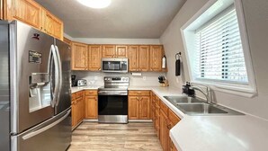 A modern kitchen with wooden cabinets, stainless steel appliances, and a window providing natural light.
