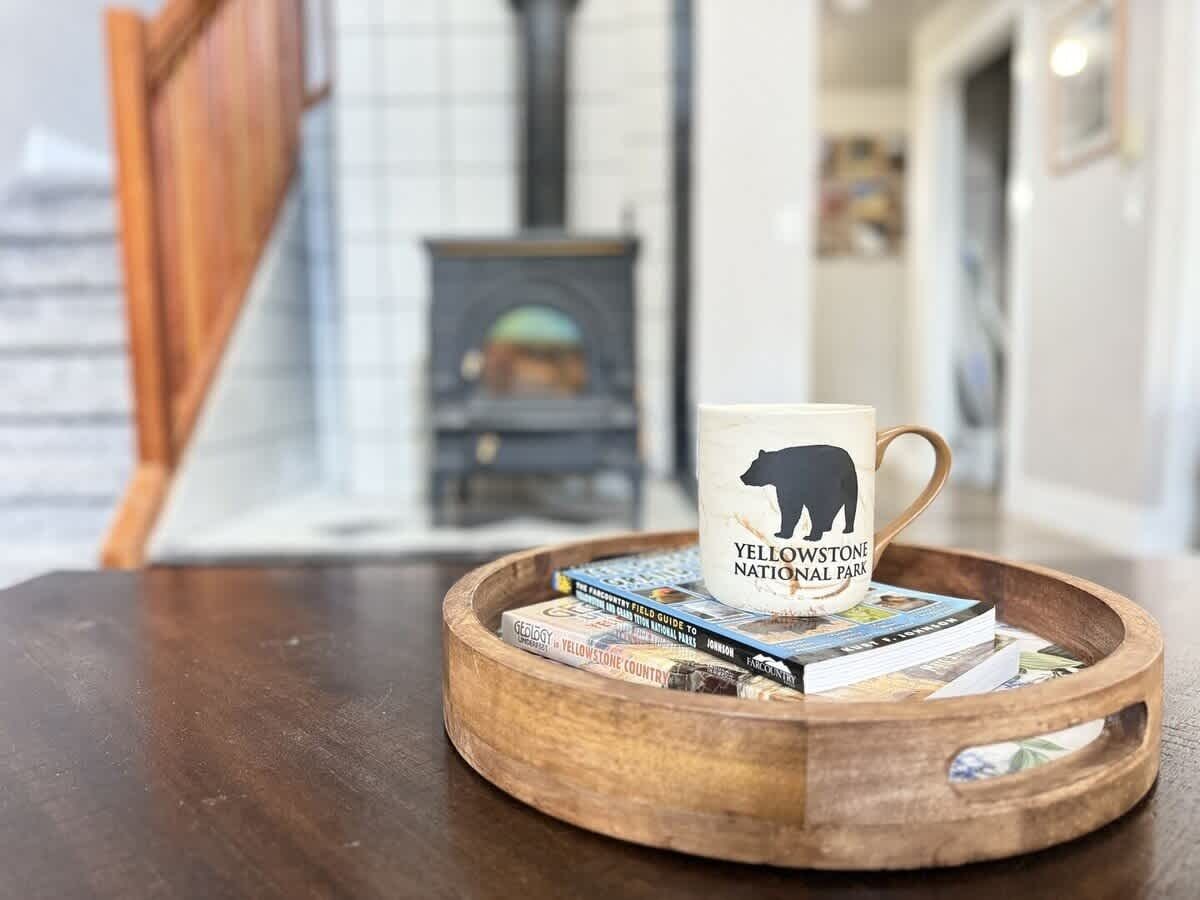 Ein Holztischchen mit einer Tasse, beschriftet mit 'Yellowstone National Park', und Büchern darauf.