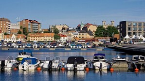 Uma marina com vários barcos atracados, rodeada por edifícios e um céu claro.