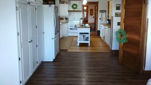 A kitchen with white cabinets, a wooden floor, and a central island. -  Bloomin Pickets Farmhouse Stay OR Ladies Craft Retreat! (Monroe)