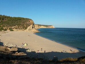 En strand med en klippig brant och ett lugnt hav.