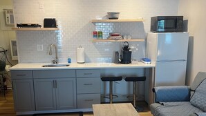 A compact kitchen with a central island, a refrigerator, a microwave, and a coffee maker.