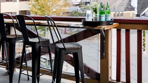 A balcony with two chairs and a table, overlooking a residential area with trees and buildings. - The Village at Palisades Tahoe Bldg 1 - Chic Condo with Prime View (Olympic Valley)