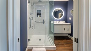 A modern bathroom with a glass-enclosed shower, a vanity with a mirror, and a white cabinet. - The West Lane Inn - Deluxe Fireplace King (Ridgefield)