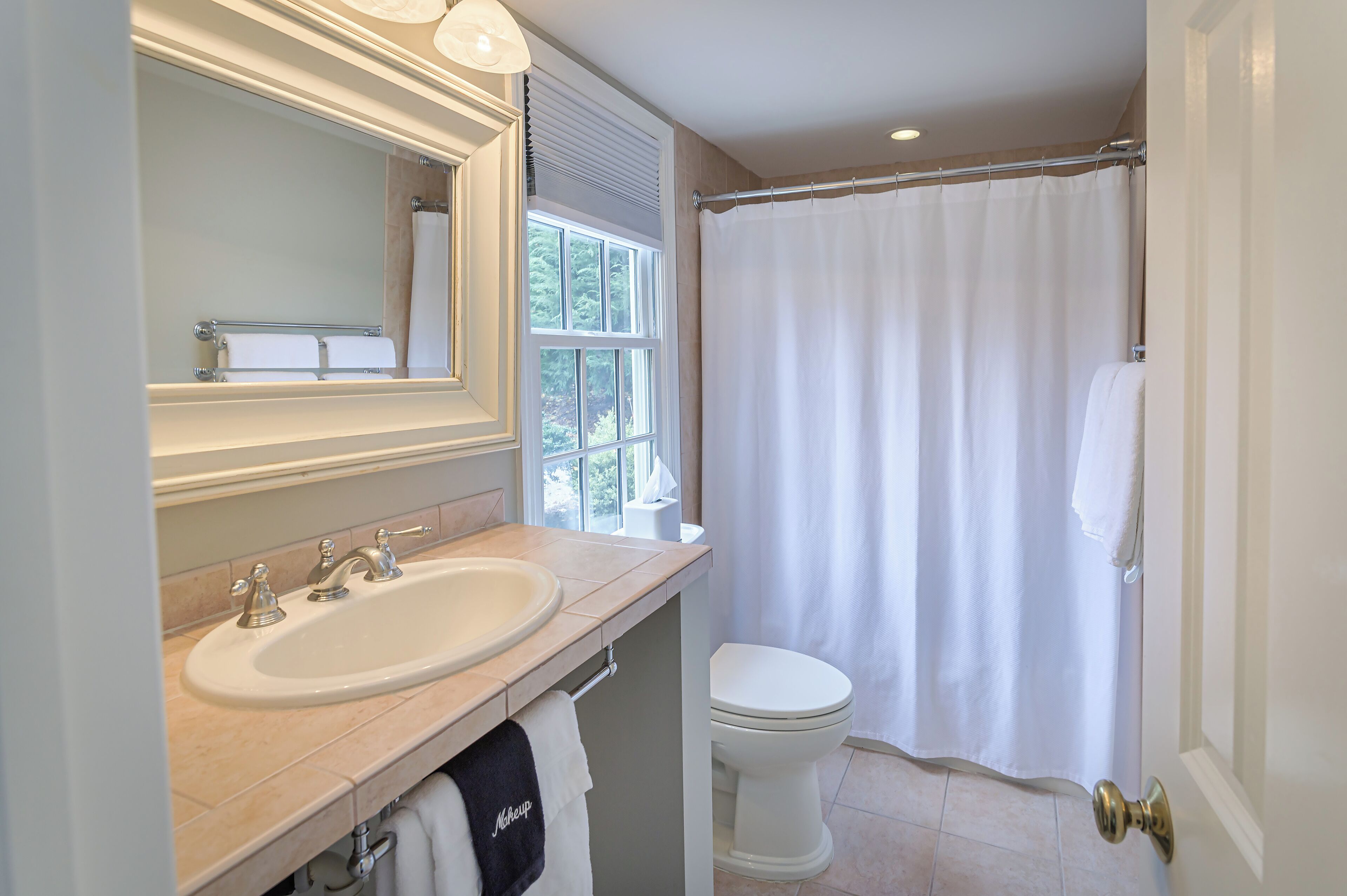 A bathroom with a sink, mirror, toilet, and a shower curtain.