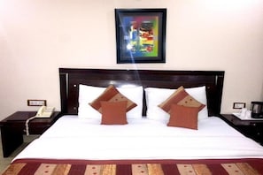 Relax in a cozy retreat with a neatly made bed, dark headboard, and framed artwork.