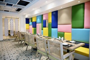 A dining area with booths and tables, featuring a modern design with geometric wall panels. - Sun City (New Delhi)