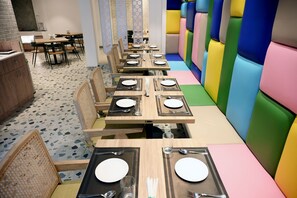 Een restaurant met meerdere tafels, klaar voor diners, met een combinatie van houten en gestoffeerde zitplaatsen.