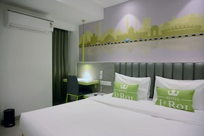 A hotel room with a bed, a desk, and a cityscape mural on the wall.