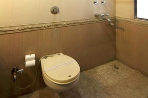 A compact bathroom with a toilet and shower area, featuring decorative molding and tile flooring.