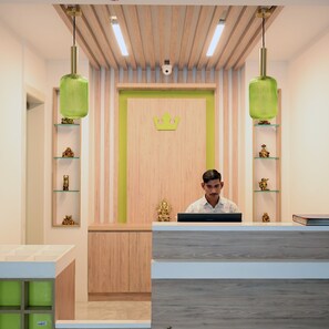A reception desk with a crown-shaped decoration, wooden paneling, and green shelves with golden statues. - Sun City (New Delhi)