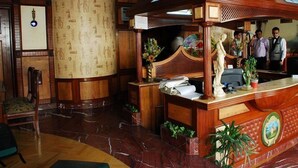 A reception area with a wooden reception desk, a large wall with hieroglyphs, and a ceiling with a mural. - Sunstar Grand (New Delhi)