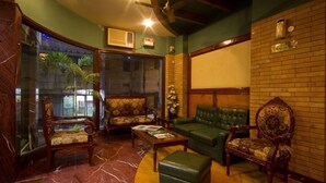 A room with a green sofa, a wooden chair, a coffee table, and a fireplace. - Sunstar Grand (New Delhi)