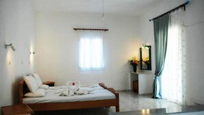 A hotel room with a bed, a bedside table, a mirror, and a window with curtains. - Zeus (Samos)