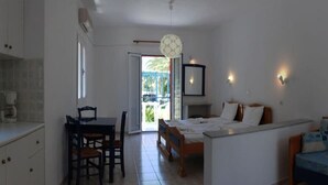 A bedroom with a bed, a desk, and a chair. There is a window and a door leading to a balcony. - Zeus (Samos)