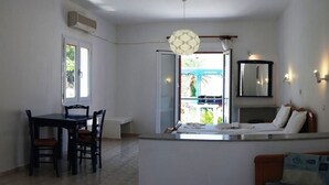 A compact kitchen with a dining area, a small bar counter, and a balcony with a view. - Zeus (Samos)