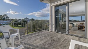 A modern balcony with a view of the surrounding landscape, including a mountain and a road. - Pauanui Hangar Retreat - Pauanui Holiday Home (Pauanui)