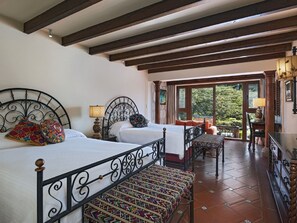 Habitación con dos camas, una mesita y vistas al exterior.