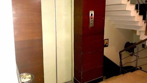 Un ascensor con pared roja y puerta blanca, junto a una escalera con barandilla de metal.