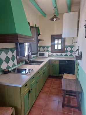 A kitchen with green cabinets, a microwave, a sink, and a wooden table.
