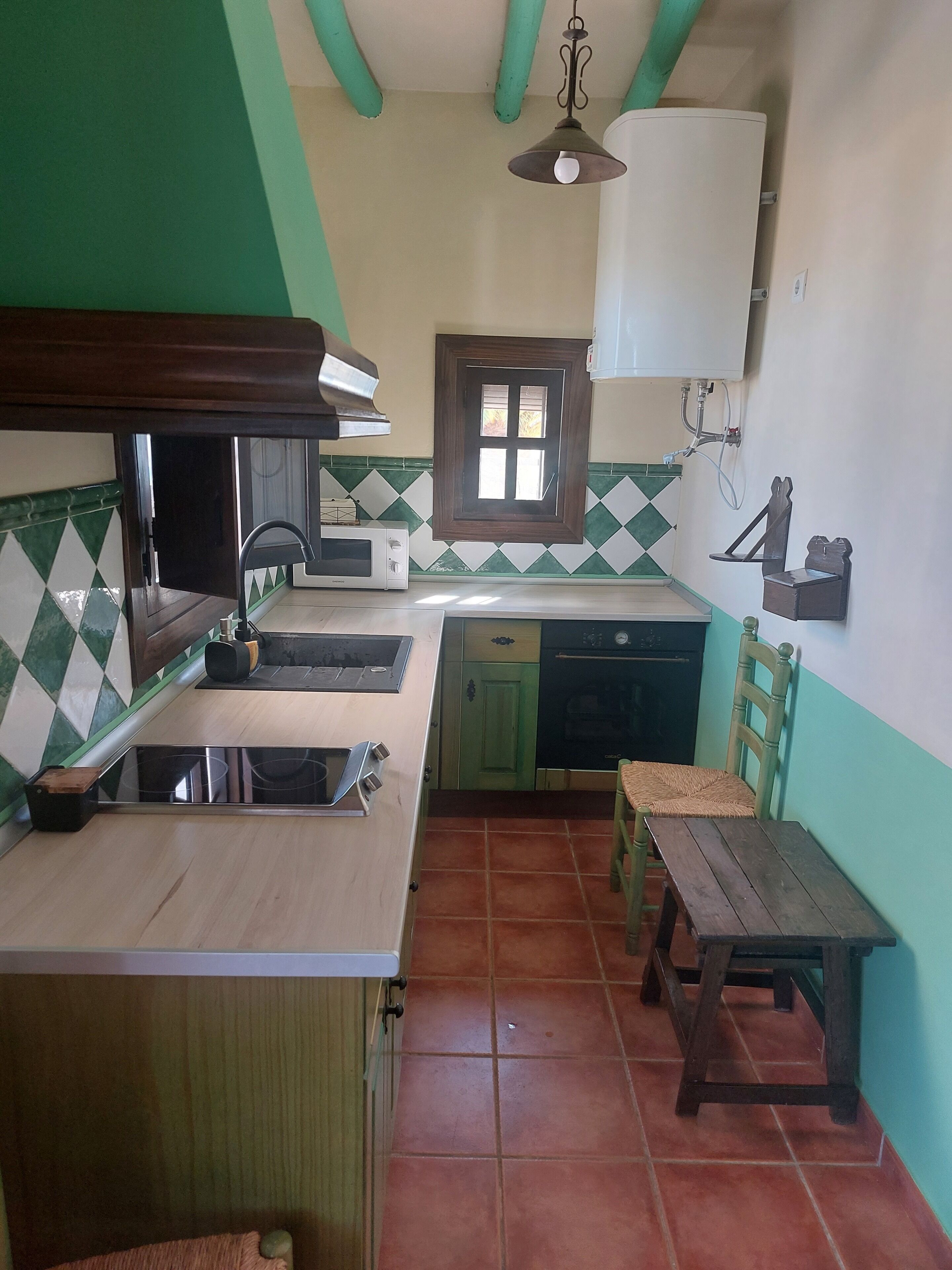 A compact kitchen with a microwave, sink, and wooden table.