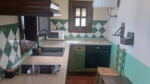 A compact kitchen with a microwave, sink, and wooden table. - RURAL HOUSE IN CASILLAS GUERRERO (Ventorros de la Laguna)