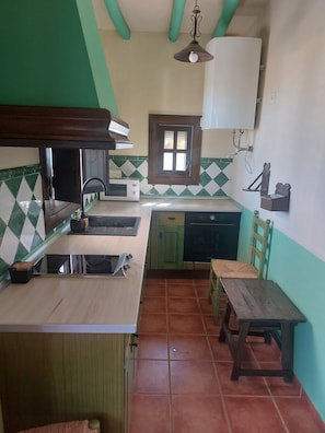 Una cucina compatta con forno a microonde, lavello e tavolo di legno.
