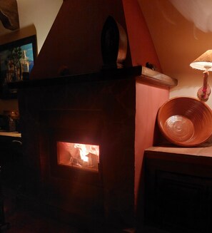 A fireplace with a visible fire, a lamp, and a decorative bowl on a table.
