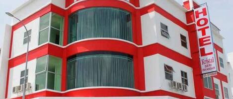 Un hotel con una fachada distintiva de color rojo y blanco, ventanas grandes y un letrero llamativo.