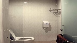 A modern bathroom with a toilet, a towel rack, and a glass shower enclosure. - HOTEL KRISTAL SERI ISKANDAR (Bota)