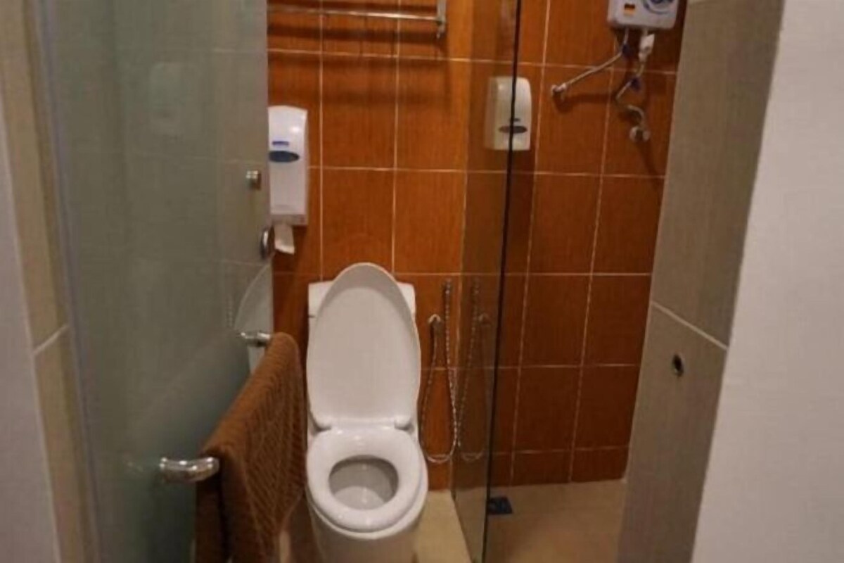 A bathroom with a toilet, a hand dryer, and a shower area.