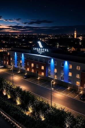 A hotel with a prominent sign, multiple floors, and a parking lot.