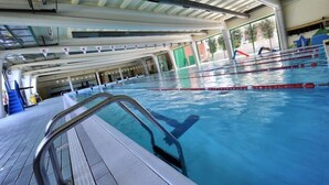 Une piscine intérieure dotée de couloirs clairement délimités, d’un plongeoir et d’une zone de pont en carrelage.