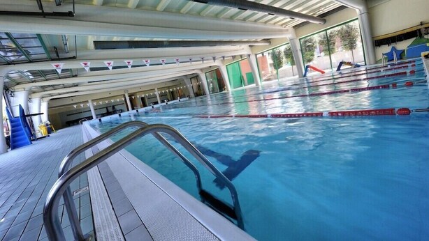 An indoor swimming pool with clear lane dividers, a diving board, and a tiled deck area. - Bes Hotel Bergamo West (Mozzo)