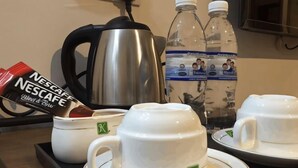 A tray with two white cups, a Nescafe coffee pod, a water bottle, and a water jug. - K GARDEN HOTEL PARIT BUNTAR (Parit Buntar)