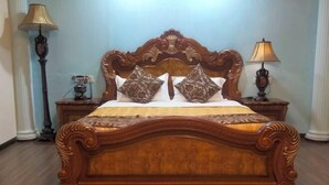A bed with an ornate headboard, two bedside lamps, and a patterned rug. - K GARDEN HOTEL PARIT BUNTAR (Parit Buntar)